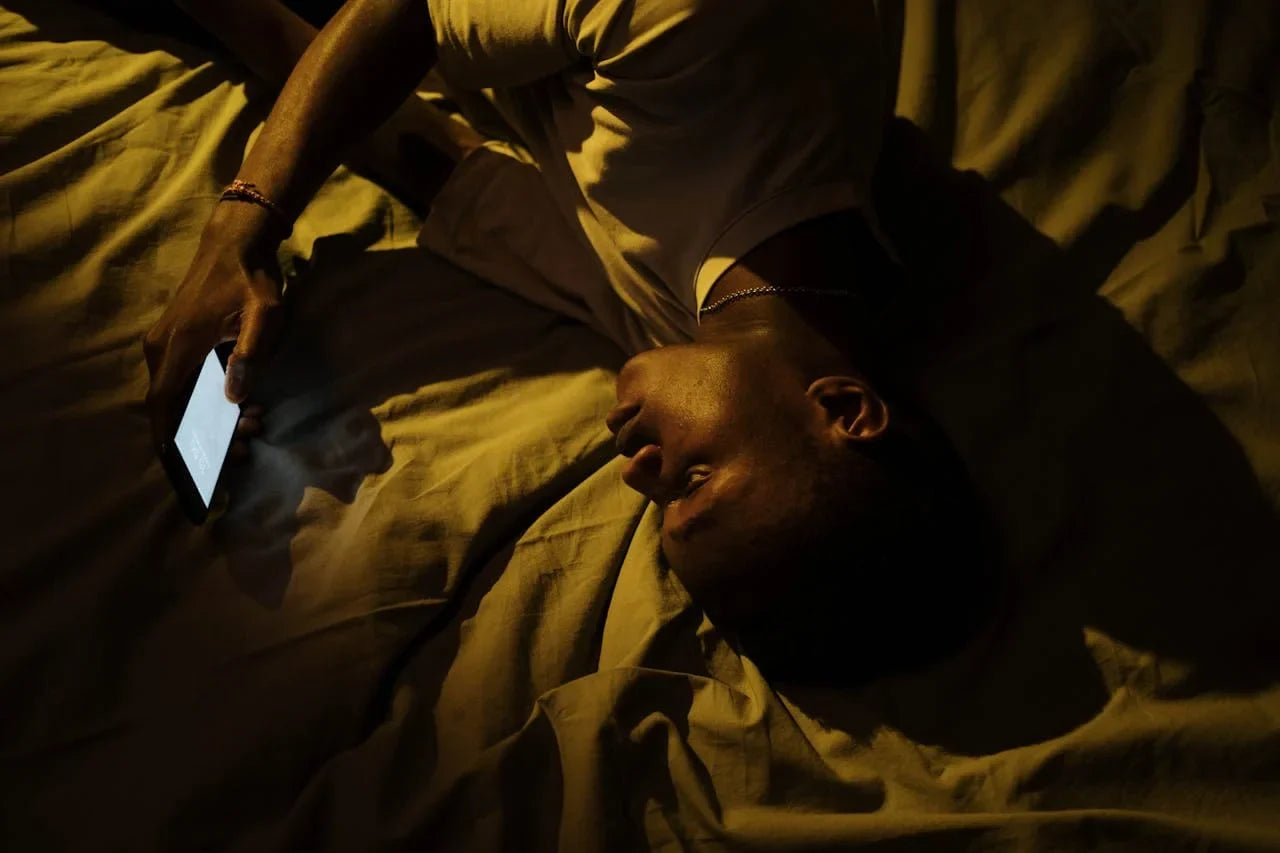 photo d'un homme allongé sur son lit entrain d'utiliser son smartphone