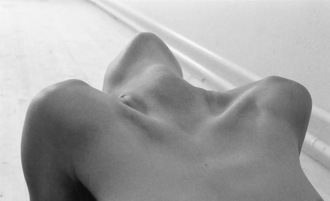 Femme en noir et blanc, penchée en arrière, montrant ses épaules et son buste, dans une pose sensuelle et intime