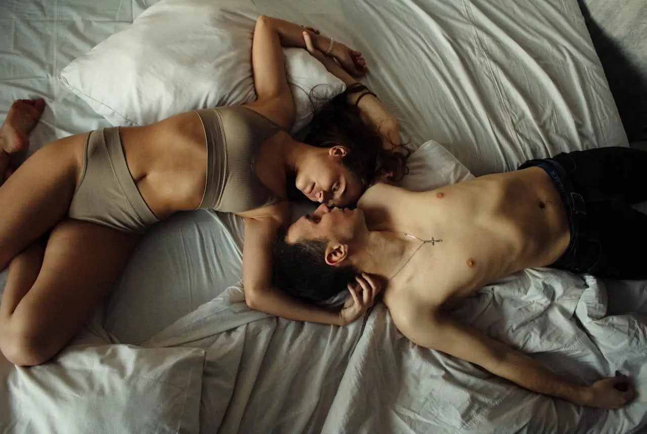Couple allongé sur un lit, en sous-vêtements, illustrant la complicité et le dialogue autour de la sexualité.
