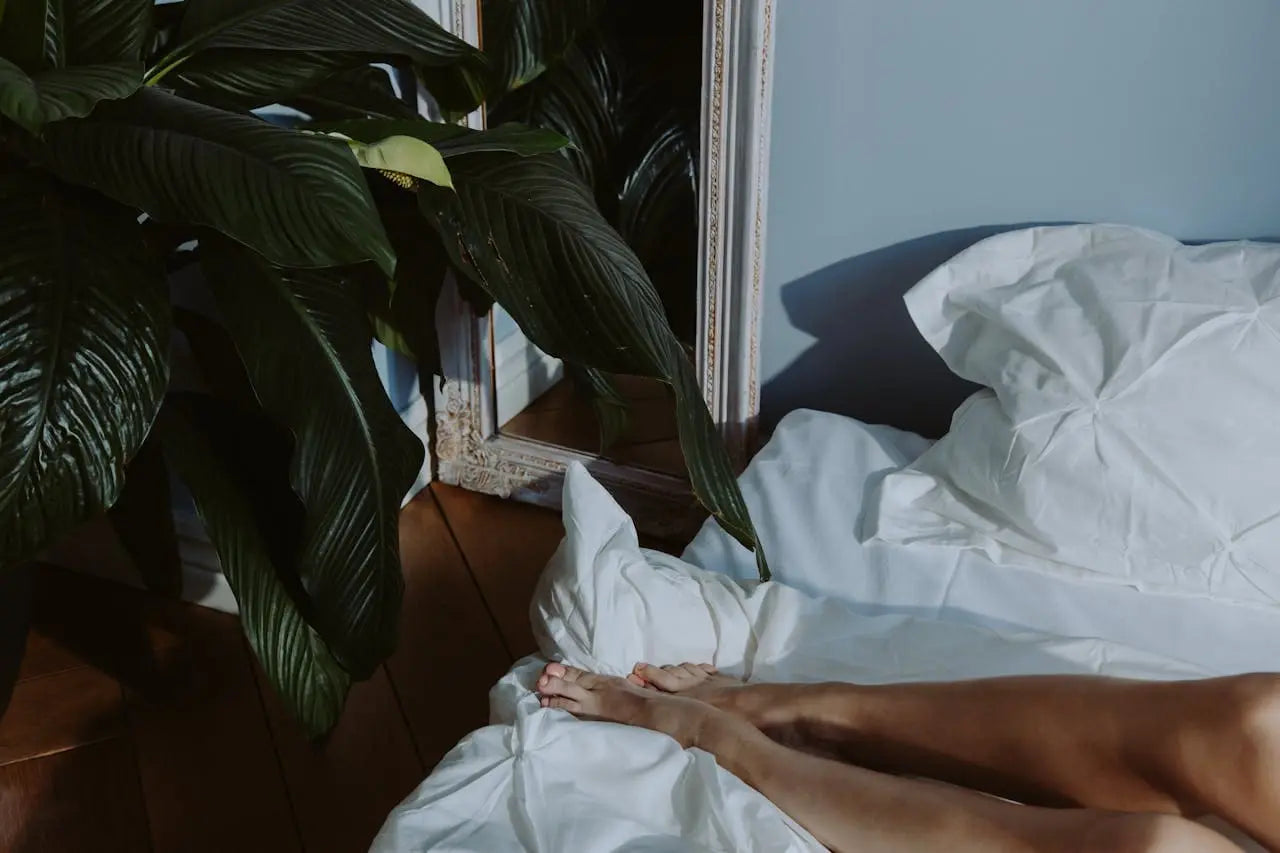 Pieds d'une femme allongée sur un lit, illustrant un article sur l'hygiène et la sécurité des sextoys